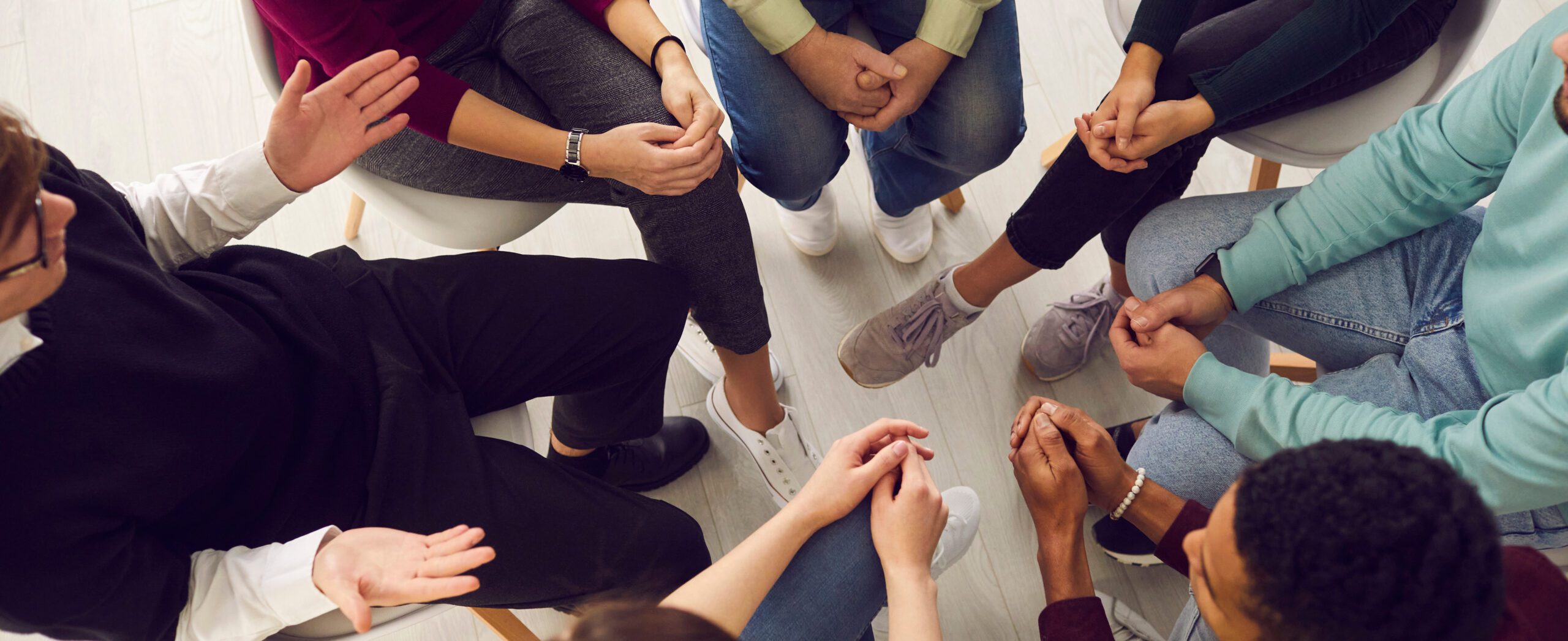 Top view of diverse people sitting in a close circle and talking to a therapist.